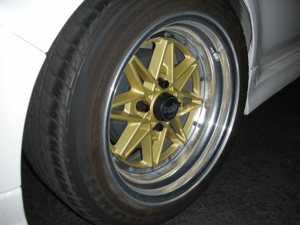 Close-up of a gold eight-spoke wheel with polished lip on a white car