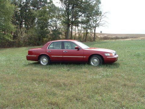 1999 Mercury Grand Marquis - Side view of a red 1999 Mercury Grand Marquis in a field.