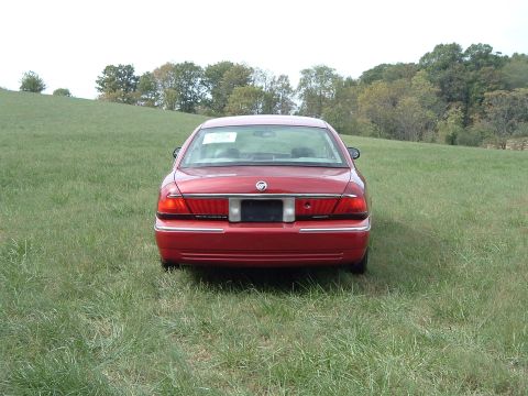 1999 Mercury Grand Marquis - Rear view of a red 1999 Mercury Grand Marquis parked in a grassy field.
