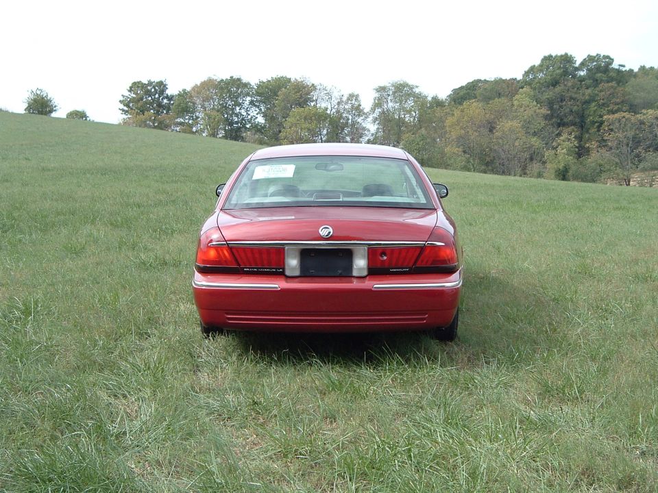 Rear view of red Mercury Grand Marquis LS sedan parked in a grassy field