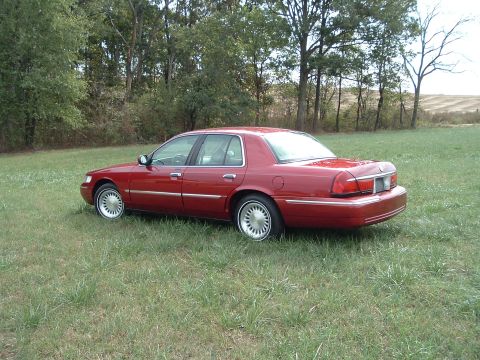 1999 Mercury Grand Marquis - Red 1999 Mercury Grand Marquis parked in a field.