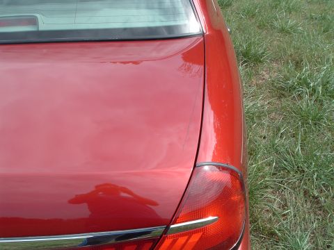 1999 Mercury Grand Marquis - Rear view of a red sedan, showing the trunk and taillight assembly.