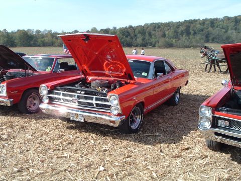 2001 Ford Taurus - A red 1967 Ford Fairlane 500 is displayed with its hood open at a car show, alongside other vehicles.