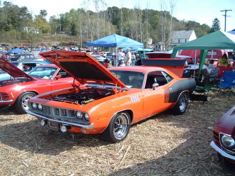 2001 Ford Taurus - Orange 1970 Plymouth Barracuda displayed at a car show with its hood open.