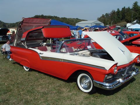 2001 Ford Taurus - A red and white 1957 Ford Fairlane convertible is displayed with its hood open at a car show.