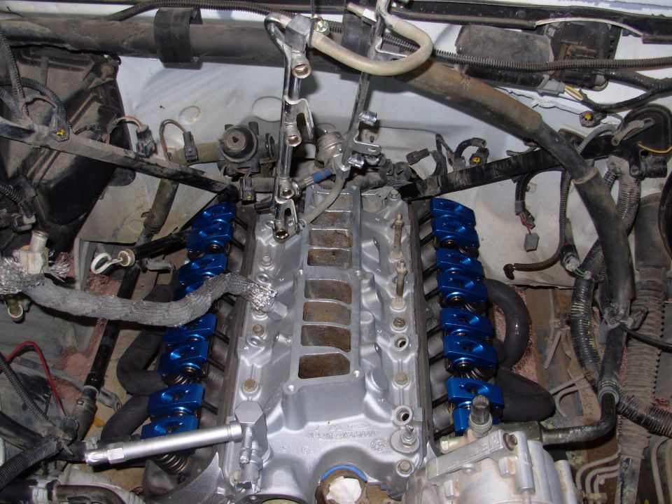 Close-up of an engine's intake manifold with blue valve covers and associated wiring