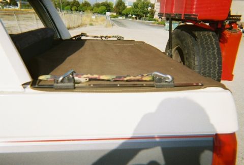 1991 Ford Bronco - Rear view of a white SUV equipped with a spare tire and red gas cans mounted on a rack.