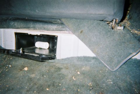 1991 Ford Bronco - Interior view of an open storage compartment located beneath a vehicle seat.