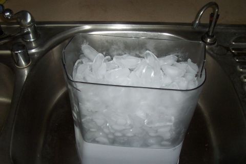 1994 Ford F-150 - A clear plastic bin filled with ice sits in a stainless steel sink next to a faucet.