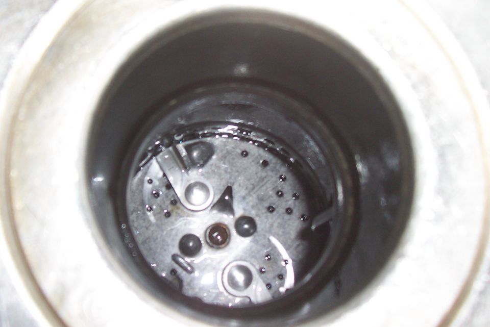 Close-up of a dirty fuel pump assembly with visible debris and liquid