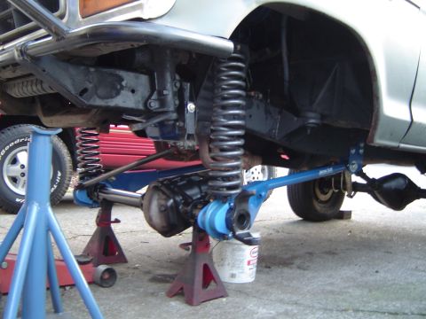 1978 Ford Bronco - Front suspension and axle of a 1978 Ford Bronco undergoing modification, supported by jack stands.