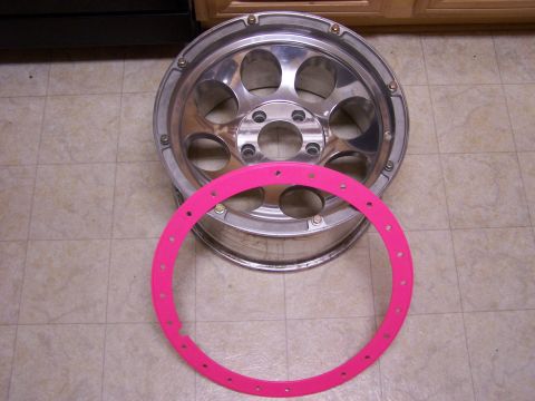1989 Ford Bronco - A chrome alloy wheel and a pink trim ring are displayed on a tiled floor.