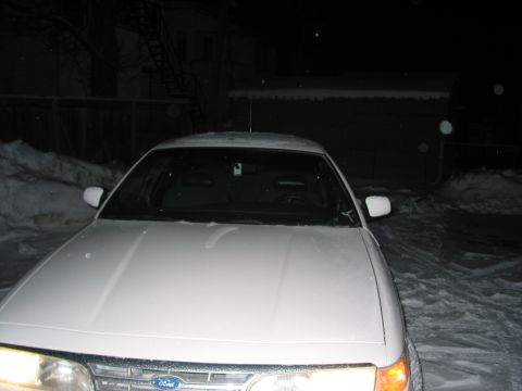 1996 Ford Crown Victoria - A white 1996 Ford Crown Victoria is parked outside in the snow during nighttime.