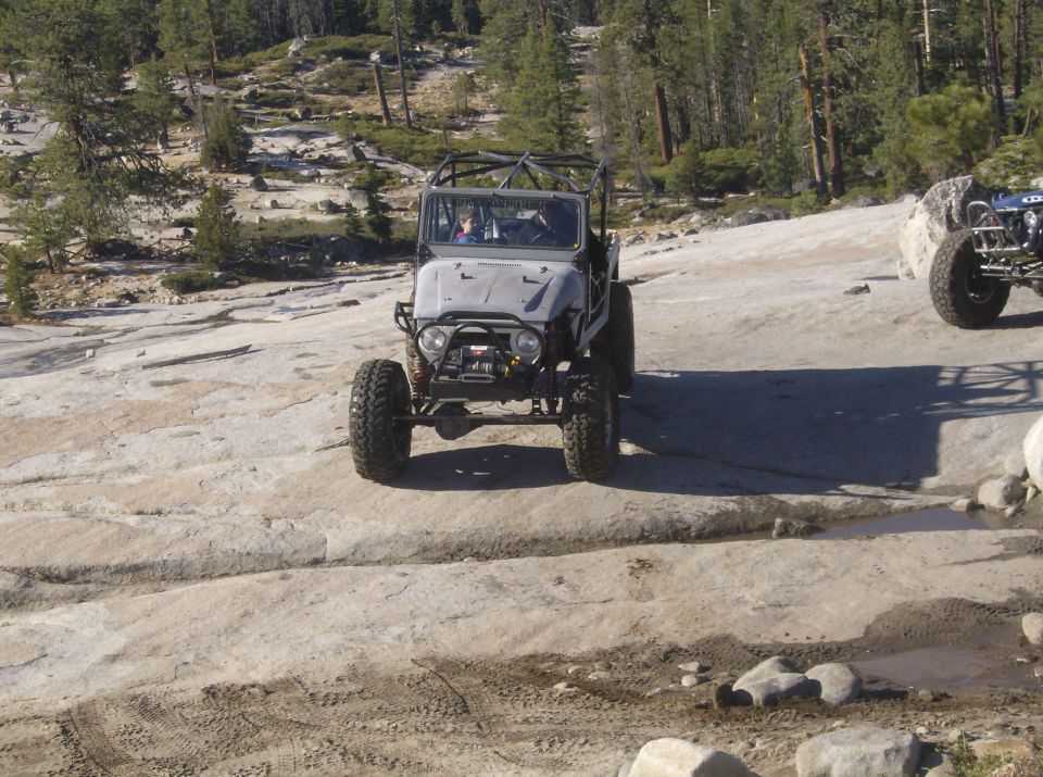 Gray off-road vehicle with a roll cage on rocky terrain