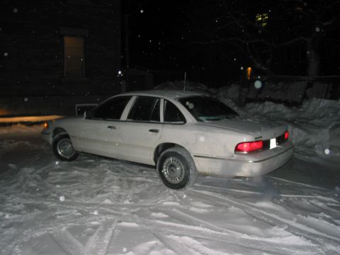 1996 Ford Crown Victoria - A white sedan sits in the snow at night, showing its side and rear quarter panel.