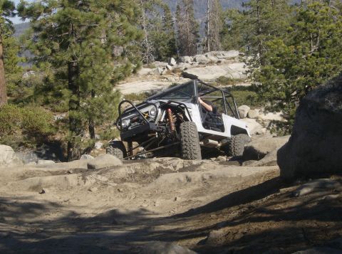 1986 Ford Bronco - This heavily modified off-road vehicle is tackling a challenging rocky path.