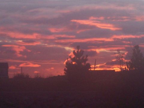 1972 Ford Ranchero - The sky is painted with dramatic pink and orange clouds during a sunset, casting a silhouette over the landscape below.