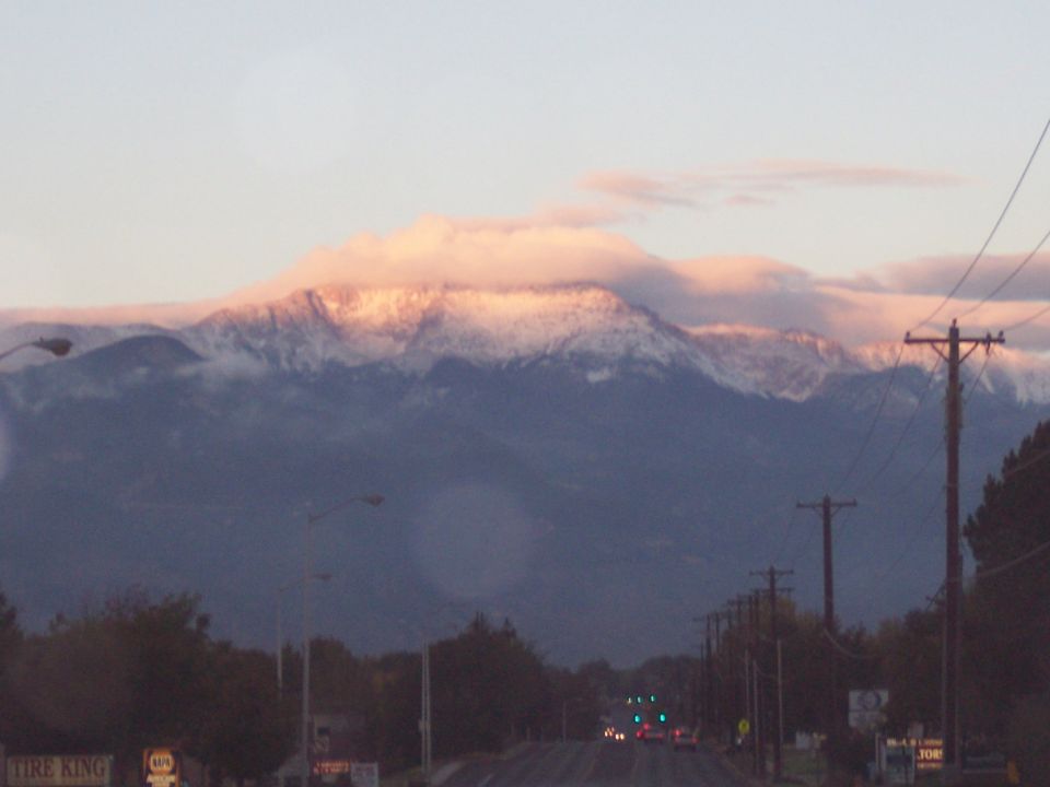snowy mountain range with pink clouds at sunset, road with power lines in foreground