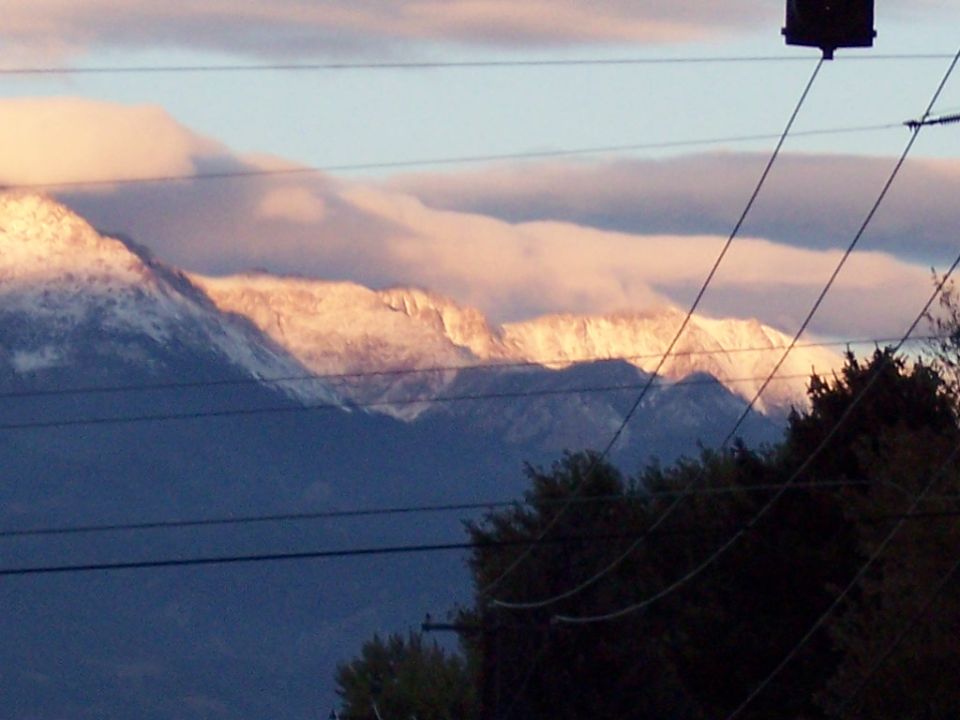 snowy mountain peaks lit by sunset, with clouds and power lines in foreground
