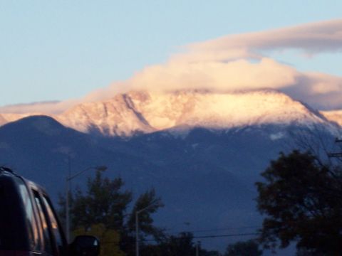 1972 Ford Ranchero - Snow-capped mountains are illuminated by the setting sun, with clouds partially obscuring the peaks.