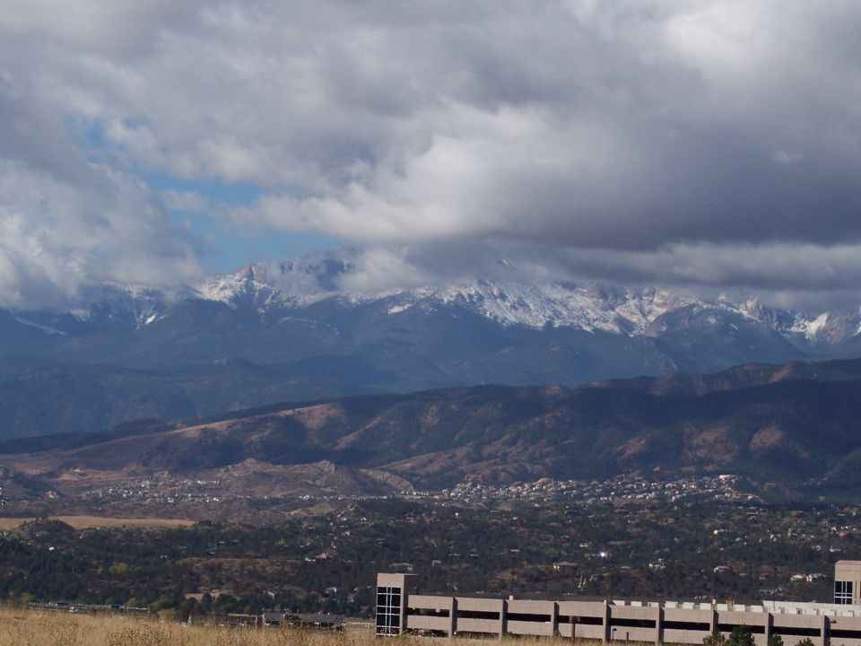 snowy mountain range above a town with clouds overhead