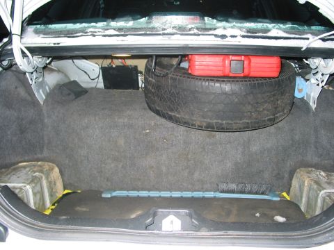 1996 Ford Crown Victoria - The trunk of a vehicle contains a spare tire, a red toolbox, and a brush, along with visible text from Supermotors.net.
