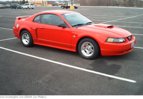 2004 Ford Mustang - A red Ford Mustang is parked in a lot with white lines.