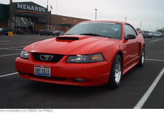 Red 2004 Ford Mustang coupe with a hood scoop, parked in a lot