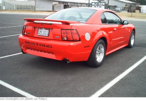 2004 Ford Mustang - Rear view of a red 2004 Ford Mustang GT with a spoiler and aftermarket wheels.