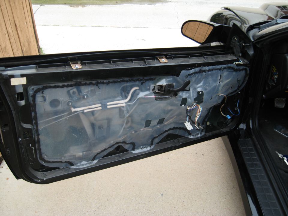 Car door with interior panel removed, showing wiring and vapor barrier