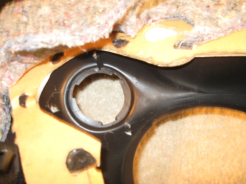 Close-up of a car's interior trim panel showing a circular cutout and textured fabric lining