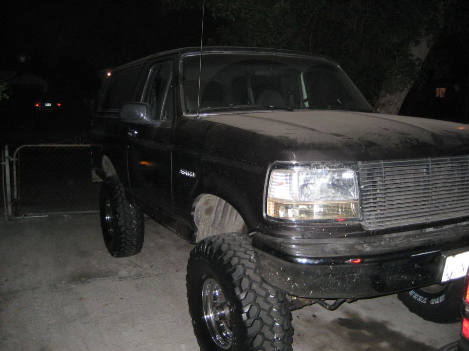 Black lifted Ford Bronco on large mud tires parked at night