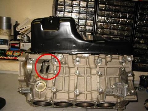 2000 Ford Crown Victoria - Close-up of an engine block and oil pan, with a red circle indicating damage to the block.