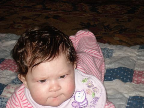 2000 Ford Crown Victoria - A baby with dark hair looks thoughtfully to the side while wearing a pink striped outfit and a bib with a bee design.