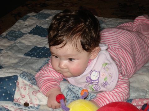 2000 Ford Crown Victoria - A baby wearing pink striped pajamas and a bib lies on a patterned quilt with toys.