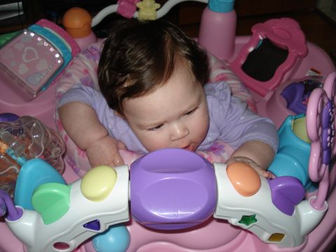 2000 Ford Crown Victoria - A baby is playing with toys in a pink activity seat.
