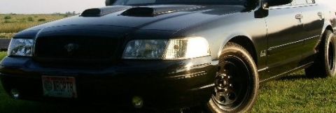 2001 Ford Crown Victoria - A black 2001 Ford Crown Victoria is shown with aftermarket hood scoops and custom wheels.
