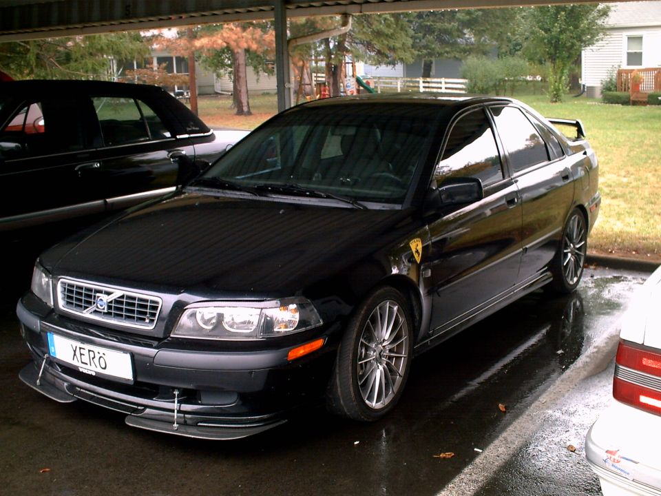 Black Volvo S40 sedan with front lip splitter and alloy wheels under a carport