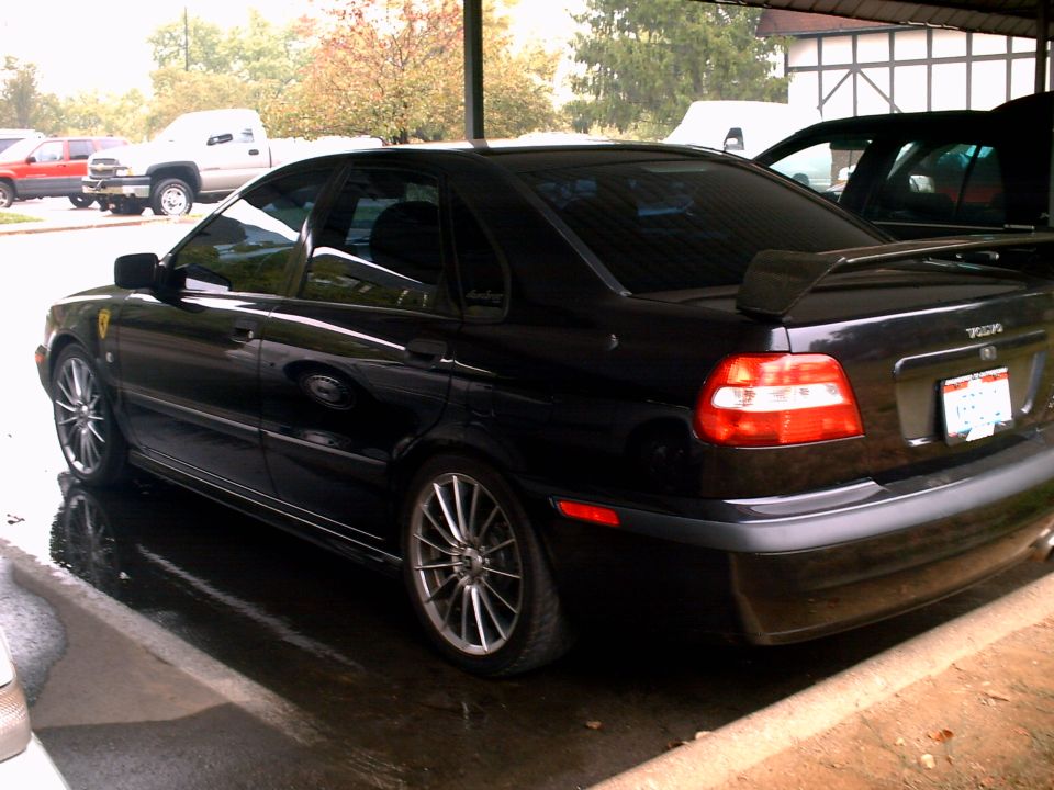 Black Volvo S40 sedan rear-side view with aftermarket wheels and trunk spoiler