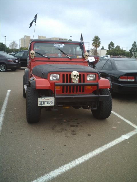 1994 Ford Bronco - This red Jeep Wrangler is decorated with skulls and flags, parked in a lot with another vehicle.