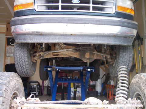 1995 Ford Bronco - The front grille and headlights of a Ford truck are visible as it is raised on a lift for maintenance.