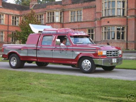1989 Ford Bronco - This custom Ford pickup truck features a crew cab and extended bed, seen here in front of a large brick building.