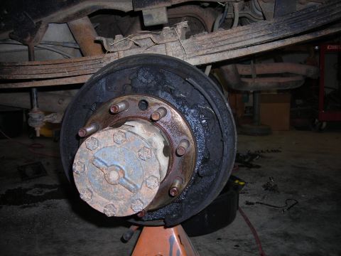 1995 Ford F-250 - Close-up of a vehicle's rear axle hub and brake drum assembly, supported by a jack stand.