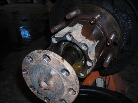 1995 Ford F-250 - Close-up view of a rusty wheel hub assembly, with a detached flange revealing the internal workings and grease.