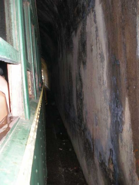 1998 Ford Crown Victoria - View along the green riveted flank of a passenger rail car as it runs through a narrow soot-blackened stone tunnel, daylight visible at the…