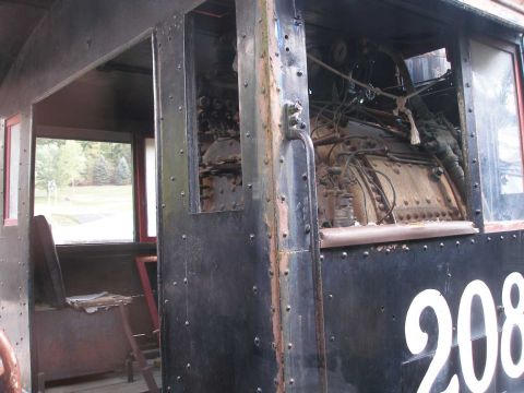 1998 Ford Crown Victoria - The riveted black steel cab of a preserved steam locomotive numbered 208, showing the backhead plumbing, gauges, valves and boiler cladding…
