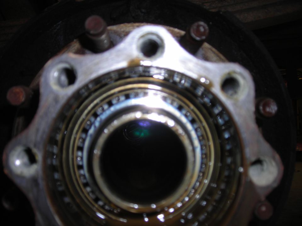 Close-up of a greased tapered roller wheel bearing inside an eight-lug truck hub