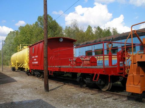 1998 Ford Crown Victoria - A row of restored railroad cars on a siding at a rail museum, including a red 'Railway Museum Fire Department' car with hose reels, a yello…