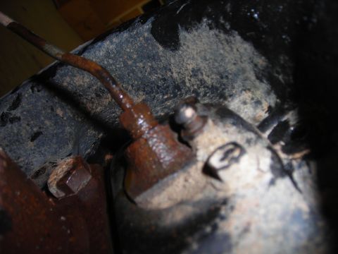 1995 Ford F-250 - Close-up view of a corroded brake line connection, likely from a truck's undercarriage.