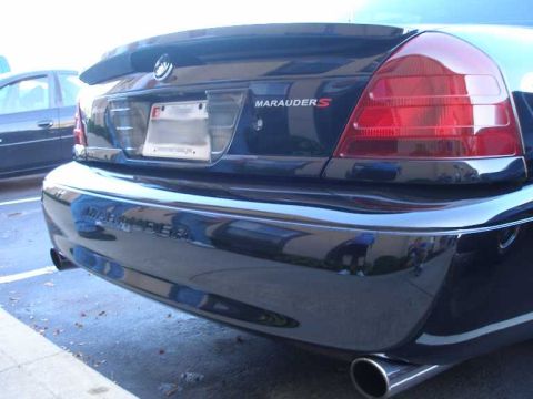 1998 Ford Crown Victoria - Rear view of a black sedan showing the driver-side taillight, chrome bumper, dual exhaust tip, and a 'MARAUDER S' badge on the trunk with '…